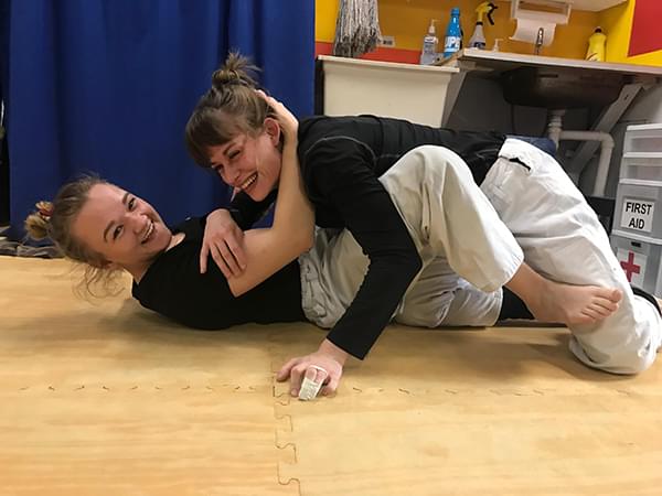 Two women grappling and laughing, jiu jitsu classes, Wise Warrior Gym in Edmonton